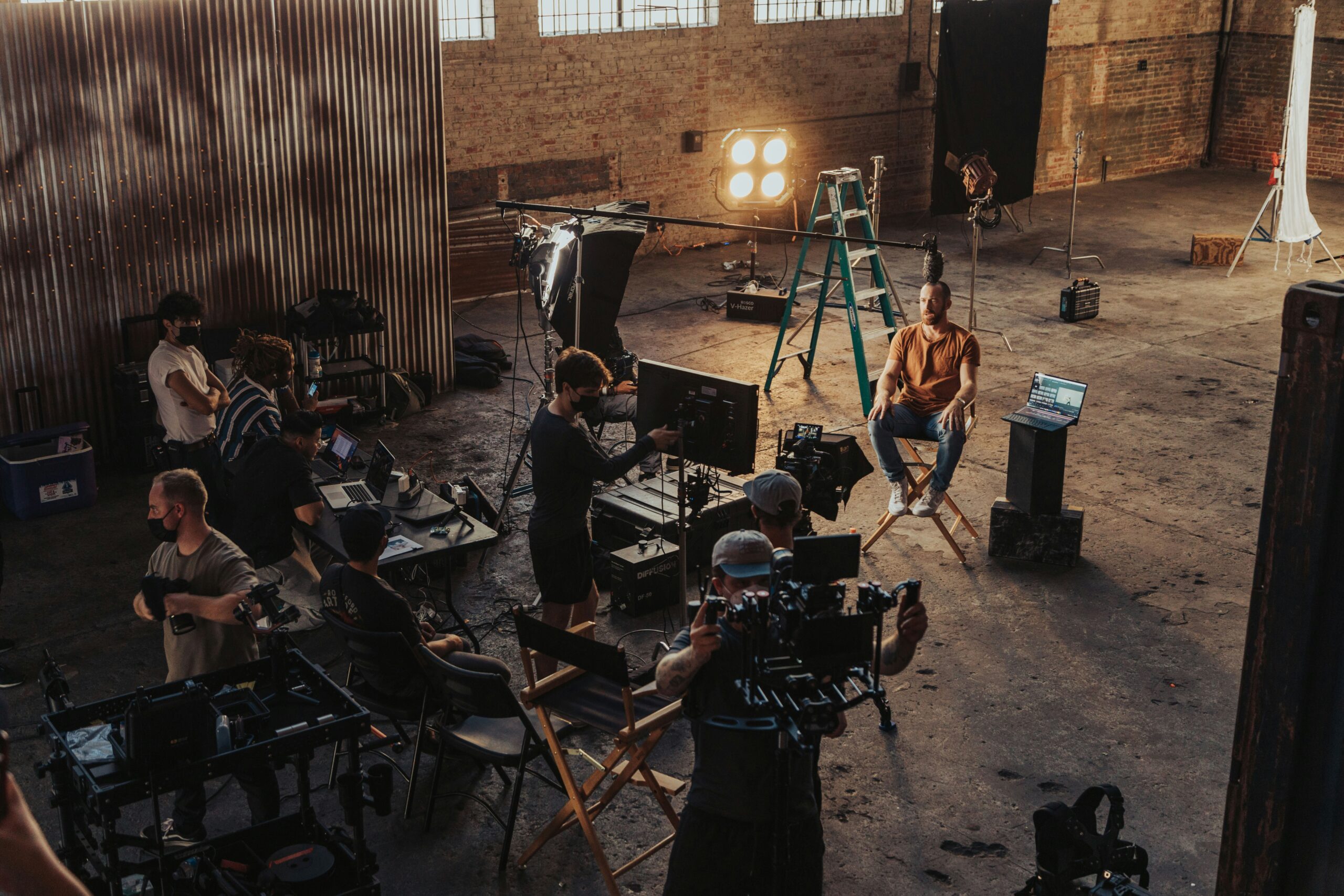 Film crew recording an interview with professional cameras, lighting, and a boom microphone