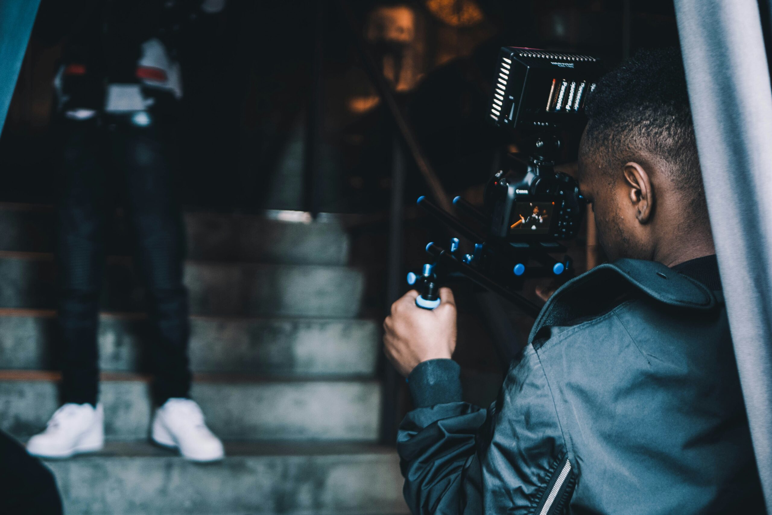 Camera operator recording a person with a shoulder-mounted camera rig